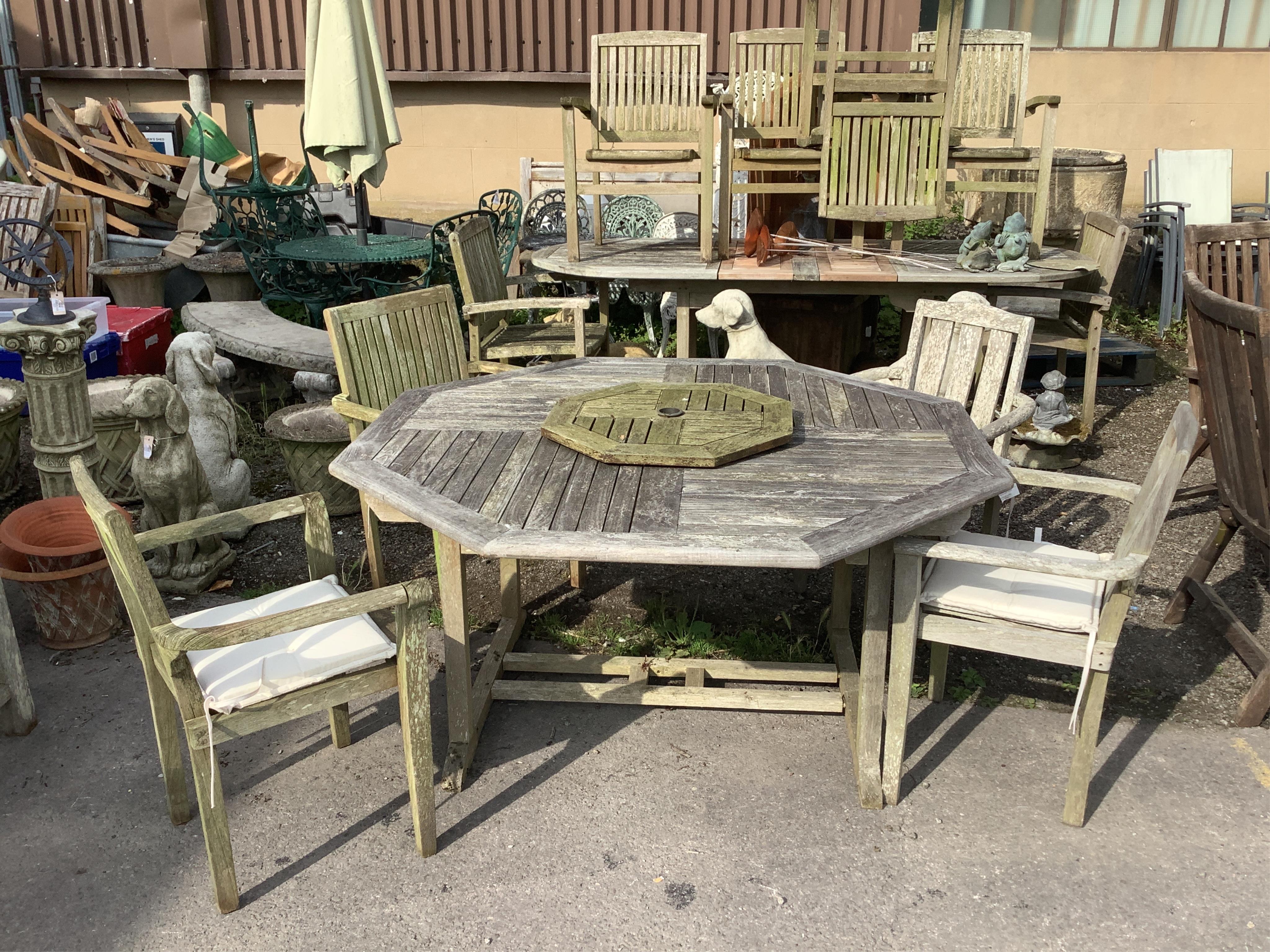A weathered teak octagonal garden table with lazy Susan width 150cm, height 75cm, and a harlequin set of four elbow chairs. Condition - fair
